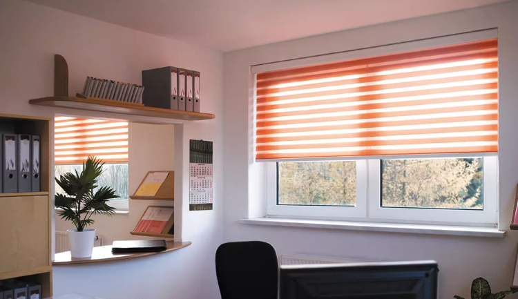 Modernes Büro mit orange-weißen Doppelrollos, weißer Fensterfront, Schreibtisch und Regal mit Aktenordnern und Zimmerpflanze.