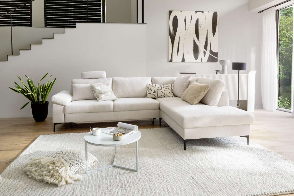 Weiße Wohnlandschaft vor einem runden Wohnzimmertisch.