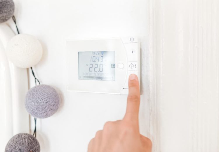 Ein Wandthermostat wird auf eine Temperatur eingestellt.