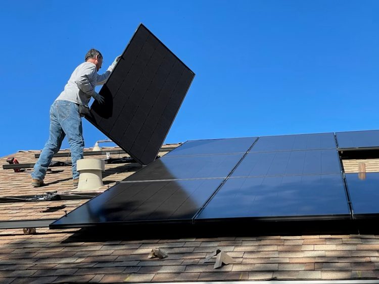 Mann montiert solaranlage auf Dach
